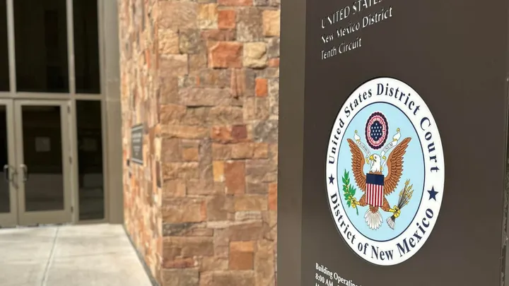 A sign bearing the seal of the U.S. District Court for the District of New Mexico stands outside the federal courthouse entrance in Las Cruces.