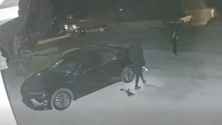 Surveillance image shows two auto burglary suspects near a parked vehicle at night in Las Cruces.