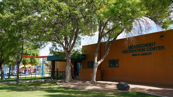 Exterior of Meerscheidt Recreation Center in Las Cruces, with trees and playground equipment visible outside.
