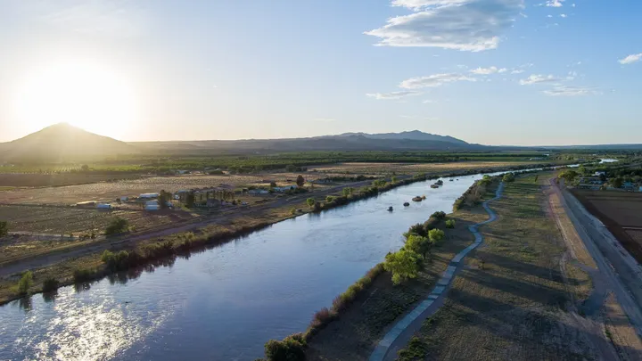 Aerial view of the Rio Grande flowing through farmland in southern New Mexico near sunset, with mountains in the distance.