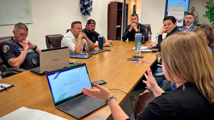 Erin Wahl leads a discussion on information literacy and artificial intelligence with Las Cruces Police Department command staff seated around a conference table.