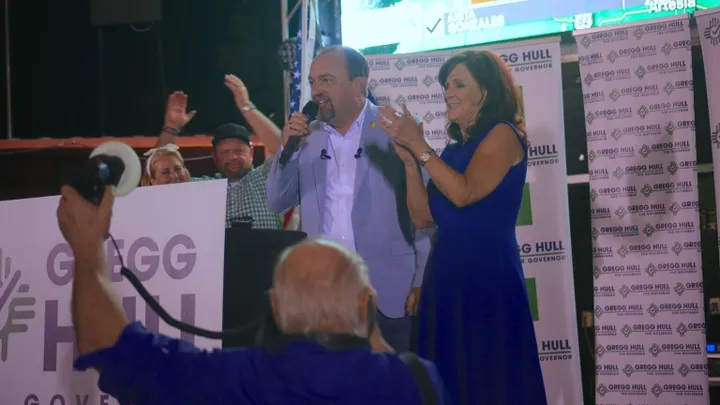 Gregg Hull speaks into a microphone beside his wife, Carrie, at an election-night event after winning the Republican nomination for New Mexico governor.