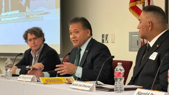 Former Las Cruces Mayor Ken Miyagishima speaks during a town hall panel while two other panelists sit beside him.