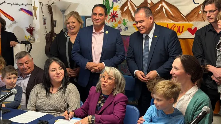 Gov. Michelle Lujan Grisham signs New Mexico’s universal child care initiative into law as lawmakers, children and providers stand nearby.