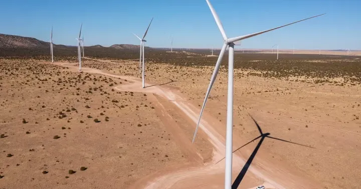 Wind turbines stand across a desert landscape as part of the SunZia transmission project.