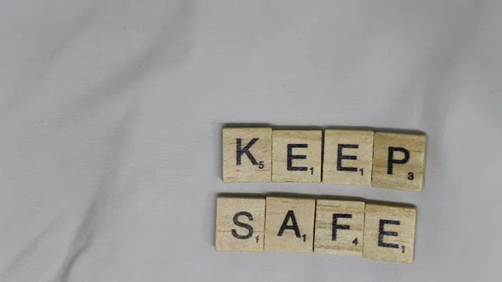 Scrabble tiles spell “keep safe” on a gray cloth background.