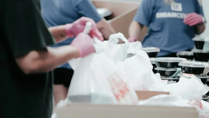 Volunteers pack food containers and bags during a food distribution event.