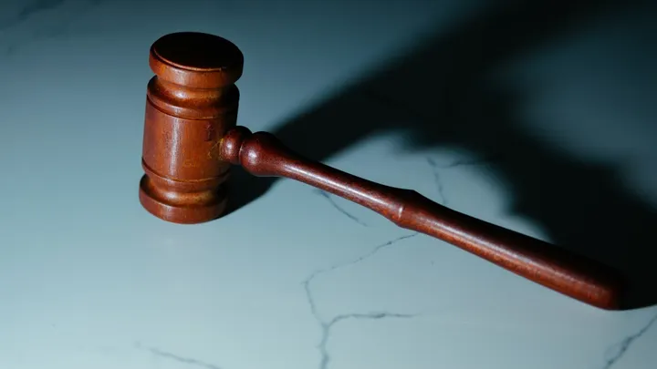 A wooden judge’s gavel rests on a table in a stock image representing a court case.