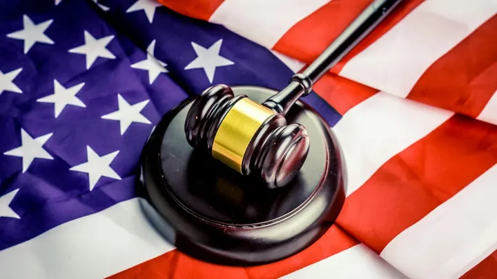 A judge’s gavel rests on an American flag.