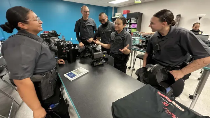 Las Cruces Police Department academy recruits talk around a classroom table during training.