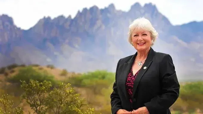 State Rep. Joanne Ferrary stands outdoors with the Organ Mountains behind her in a campaign photo.