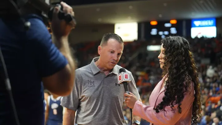 NM State men’s basketball coach Jason Hooten speaks into an ESPN microphone during a courtside interview.
