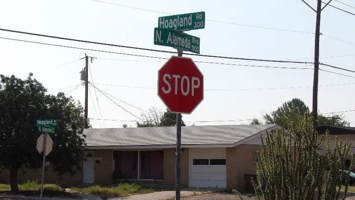A stop sign and street signs mark the intersection of N. Alameda Boulevard and Hoagland Road in Las Cruces.
