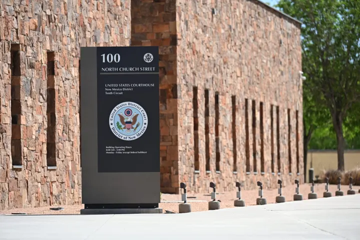 A sign identifies the U.S. Courthouse at 100 N. Church St. in Las Cruces beside the building’s stone exterior.