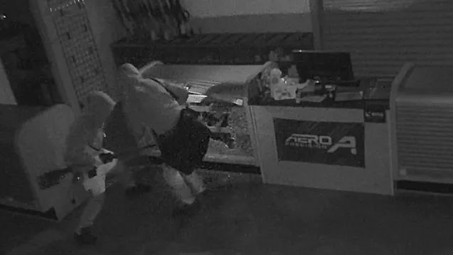 Black-and-white surveillance image showing two people moving through Strykers Shooting World during a November 2025 burglary.
