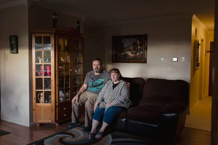 Thaddeus “Tuk” Koslik and his wife, Tracie Koslik, sit together on a couch in their Albuquerque home.