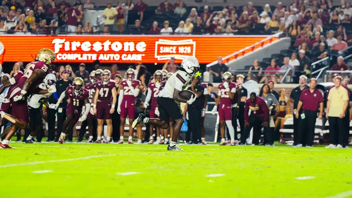 New Mexico State wide receiver TK King runs with the ball against Florida State as Seminoles defenders pursue him from behind.
