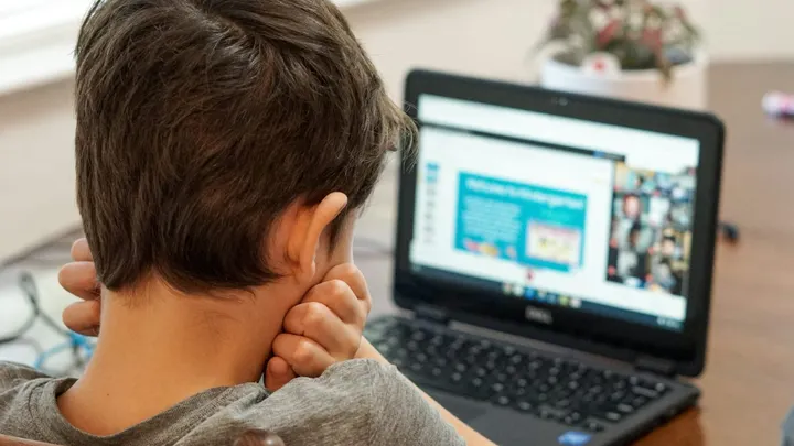 A student sits in front of a laptop during an online lesson.