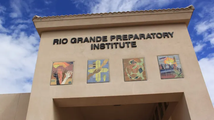 Exterior of Rio Grande Preparatory Institute in Las Cruces, with the school name displayed above colorful tile artwork on the building.