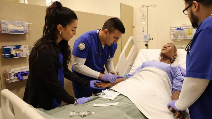 Doña Ana Community College nursing students practice inserting an IV into a patient mannequin in a simulation lab.