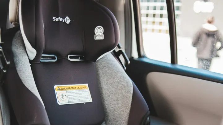 A black and gray child safety seat is installed in the back seat of a vehicle.