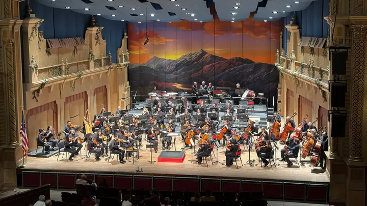 El Paso Symphony Orchestra musicians perform onstage at the Plaza Theatre, framed by ornate balconies and a painted mountain backdrop.