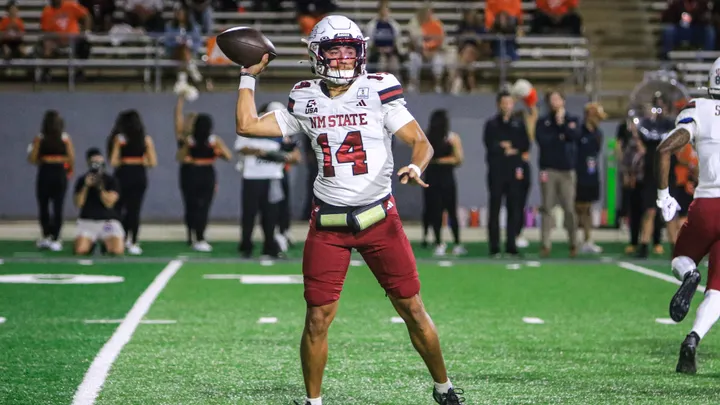 NM State quarterback Adam Damante (14) prepares to throw a pass against Sam Houston, wearing a white Aggies jersey and crimson pants.