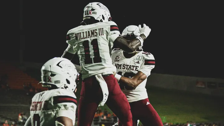 NM State wide receiver AJ Williams III (11) leaps into a celebration with teammates during the Aggies' road victory over Sam Houston.