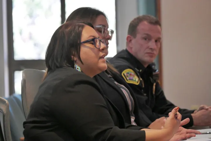 Deshawnda Chaparro speaks at a legislative committee hearing, with Valeria Garcia Tavarez and Albuquerque Police Commander Paul Haugh seated beside her.