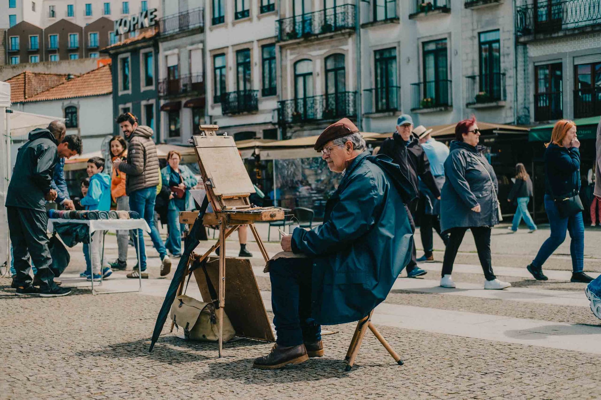 Street painter working in a busy square in Vila Nova de Gaia, Portugal photographed with the Fujifilm XF35mm f2 at f2.5 during an afternoon walk