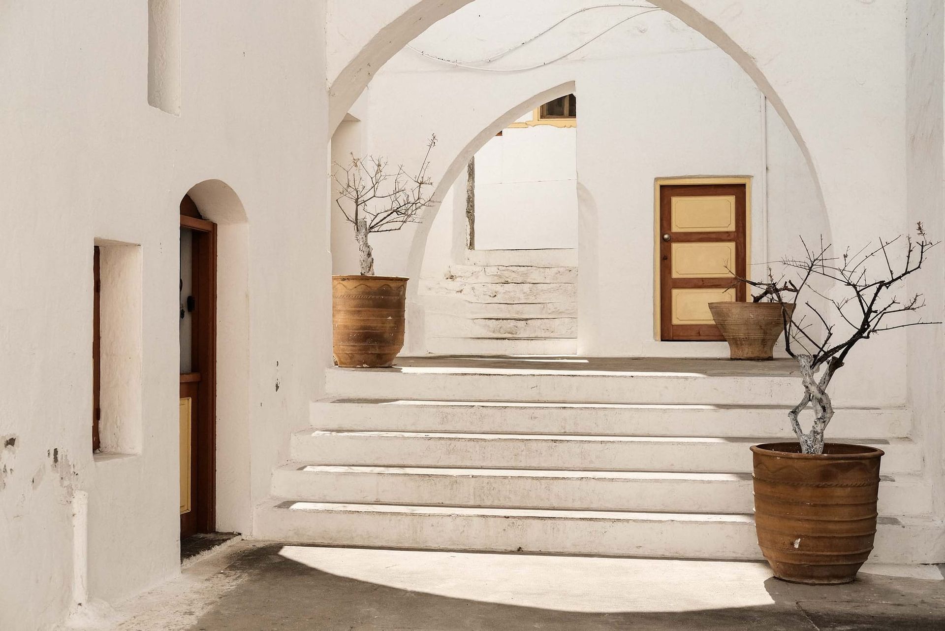 White courtyard with arches and potted trees in Rhodes, Greece photographed with the Fujifilm XF35mm f2