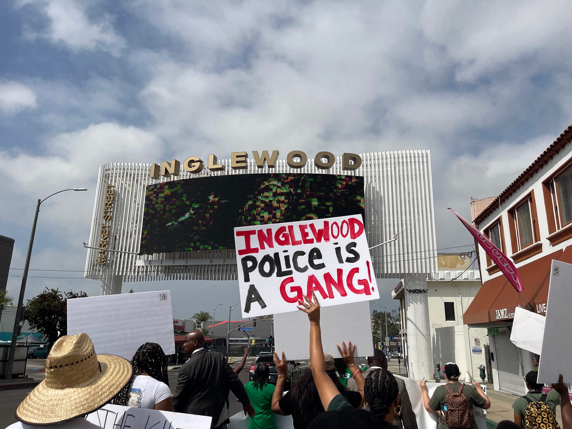 Marching under the city's new digital signs with a sign reading "Inglewood police is a gang!" September 19, 2026. Credit: Abraham Márquez