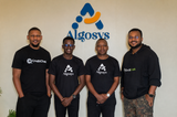 Four male executives—including Kingsley Ibe, Innocent Bigega, Simon Tayebwa, and Lionel Orishane—standing together and smiling beneath an Algosys wall logo wearing CreditChek and Algosys bran