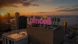 An illuminated purple Africell sign mounted on a high-rise rooftop overlooking the Luanda skyline at sunset.