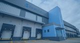 Exterior view of the Cold Solutions logistics facility, featuring a modern blue and gray facade with prominent company branding above multiple numbered loading dock bays.