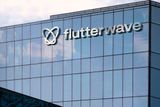 The Flutterwave logo mounted on the glass facade of a modern corporate building.