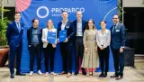 Group portrait of executives and representatives standing in front of a blue Proparco Group backdrop, with two individuals in the center holding branded folders.