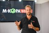 Jesse Moore, CEO and Co-Founder of M-KOPA, speaking in front of an M-KOPA Solar backdrop.