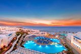 Twilight overview of a Pickalbatros coastal resort complex, highlighting illuminated outdoor swimming pools and Mediterranean-inspired guest accommodations. 