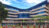 Exterior view of the Shelter Afrique Centre building in Nairobi, Kenya, featuring a multi-story glass-and-stone facade fronted by a row of African national flags along the entrance perimeter.