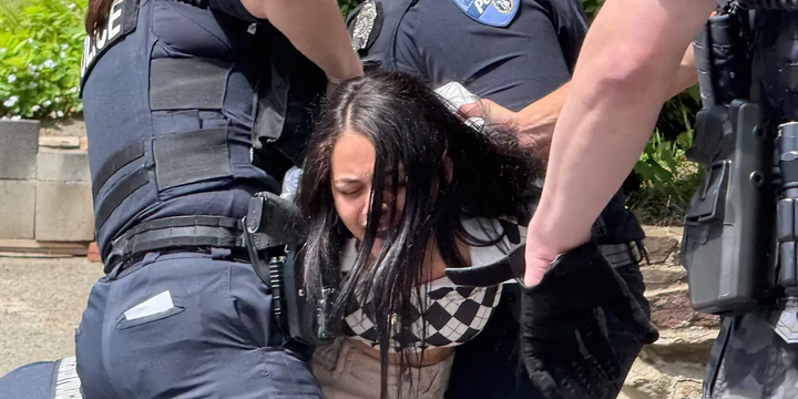 Tow police officers wrestle a young girl to the ground