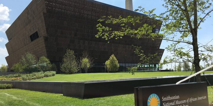 Exterior of Smithsonian National Museum of African American History and Culture with accompanying sign.