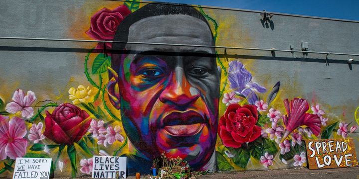 George Floyd mural with flowers and protest signs.