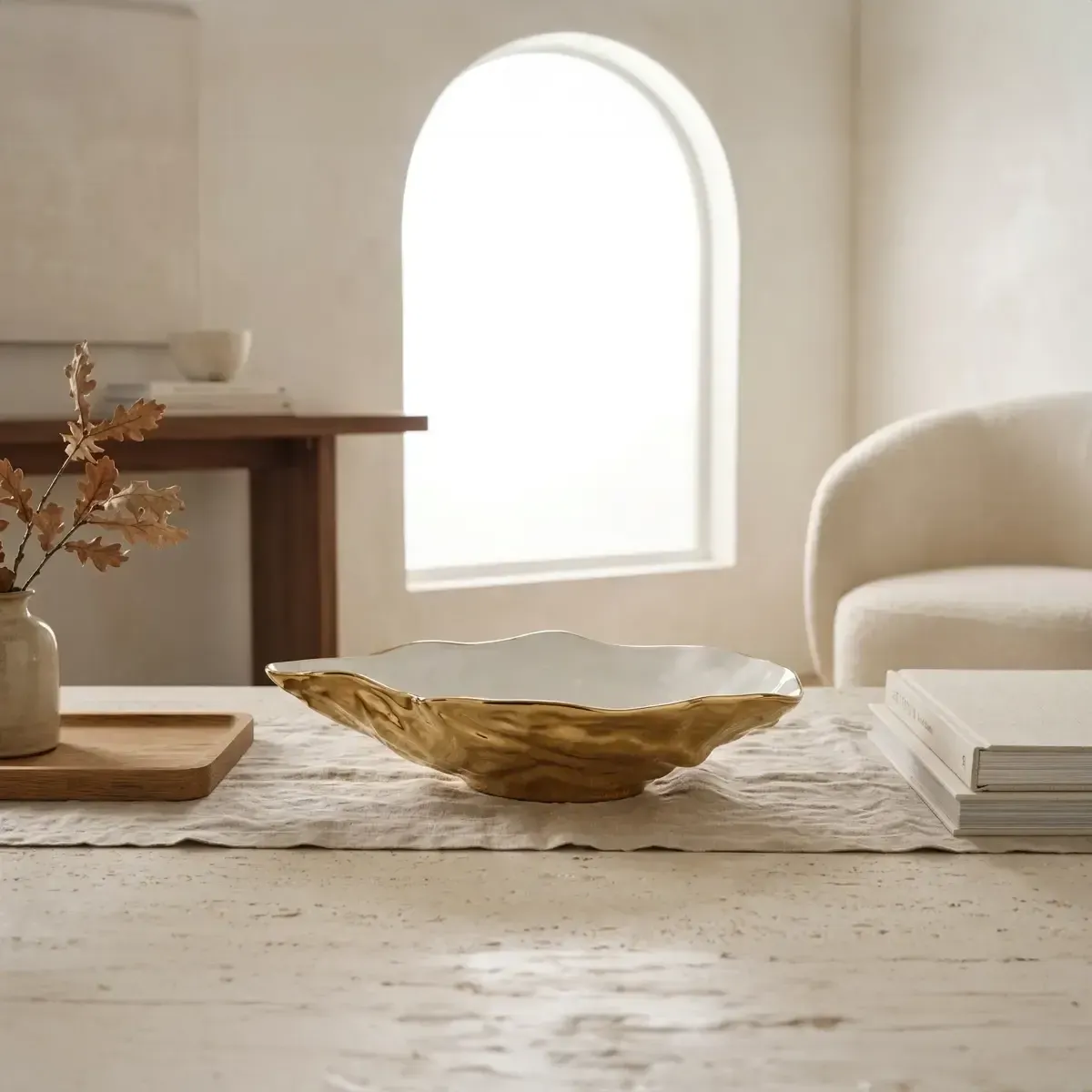 White and gold porcelain oyster-shaped bowl with a wavy rim, styled on a neutral surface in soft ambient light.