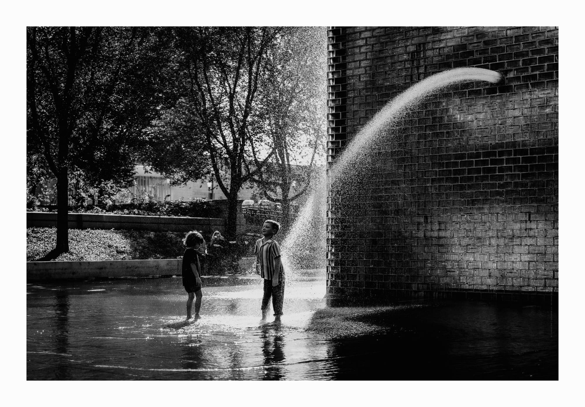 kids playing by the crown fountain in downtown Chicago, black and white monochrome fine art photo.