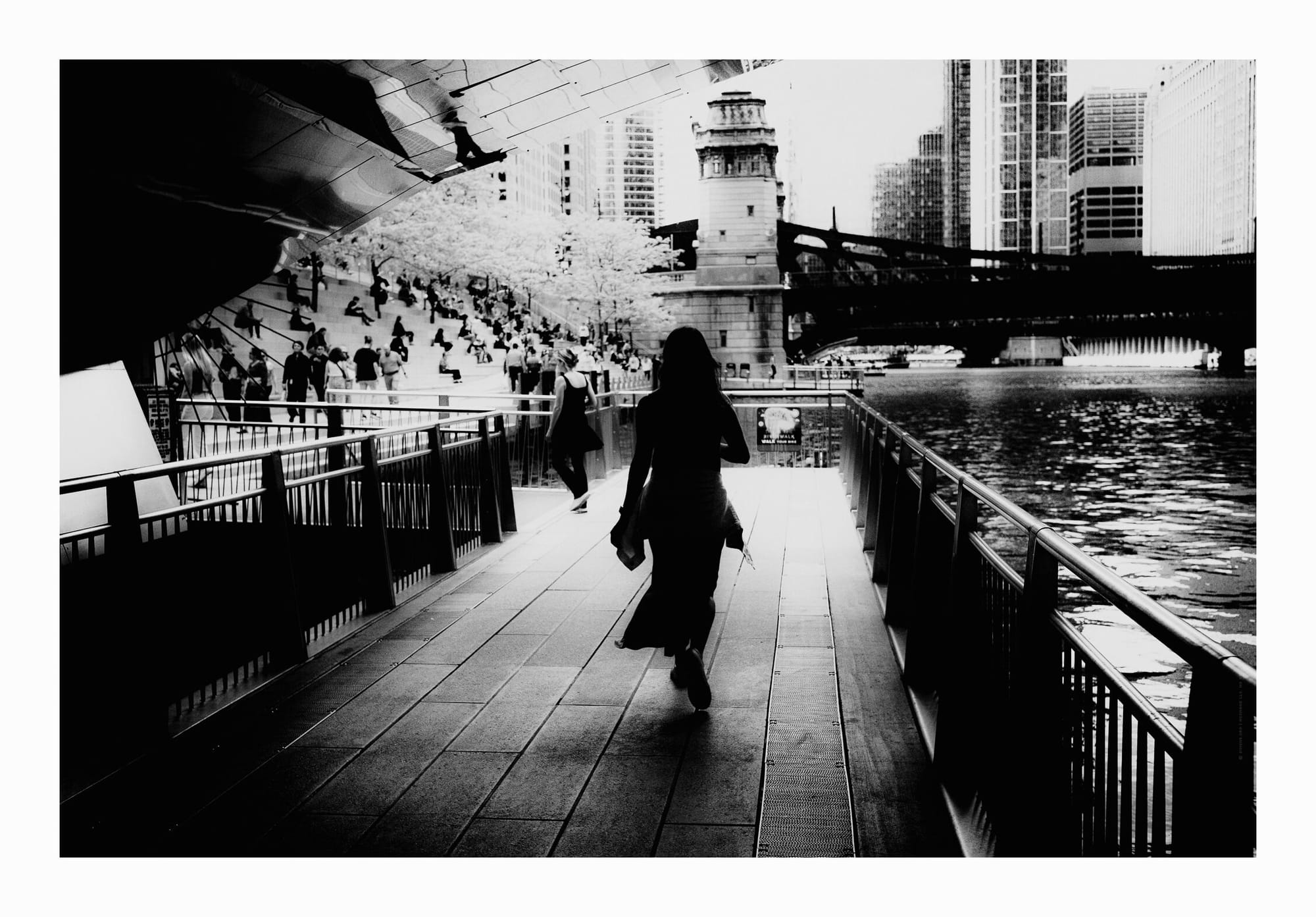 Silhouette of a woman walking by the Chicago River walk. Black and white fine art photo.