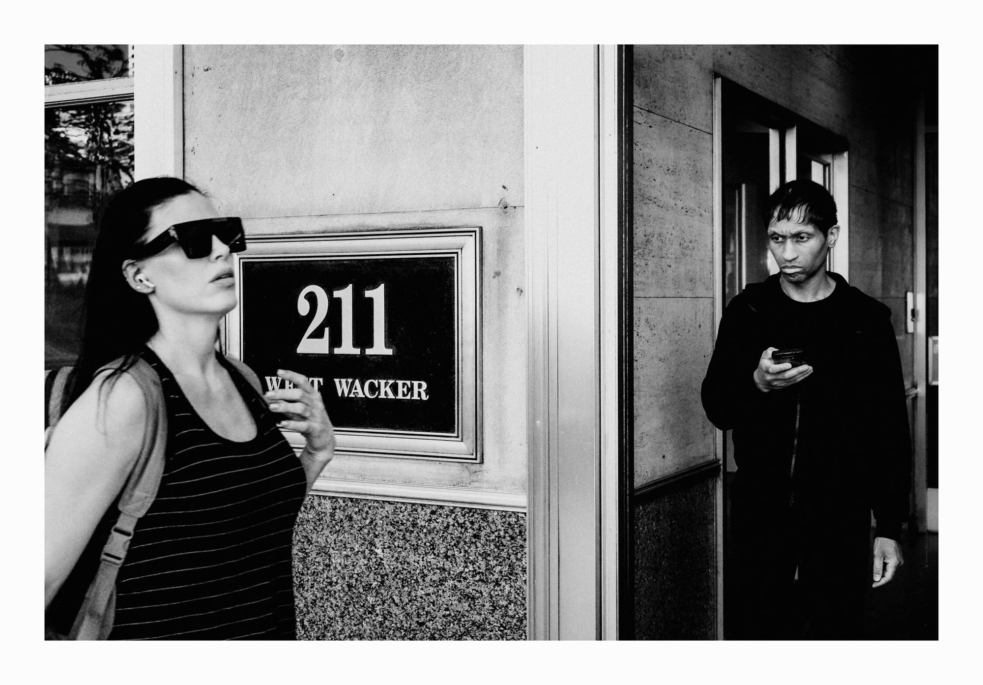 Woman walking by, man staring at her, stark hierarchical difference, downtown Chicago, black and white fine art photo.