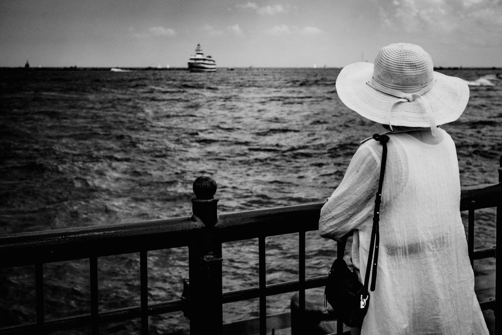 Lady in white dress looking at Ferry on Lake Michigan in the distance, black and white, fine art photo.