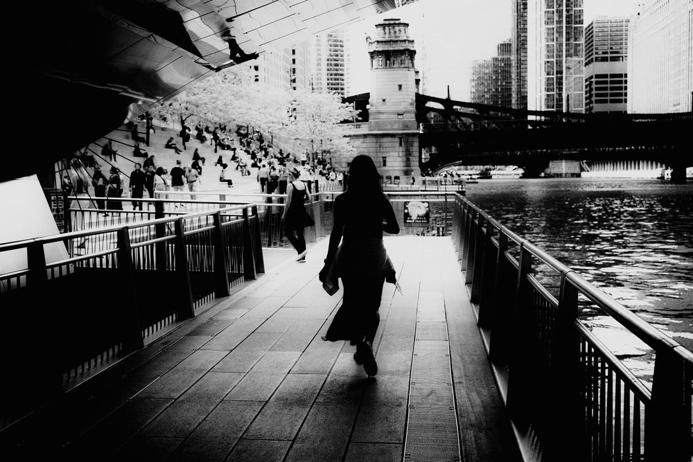 Silhouette of a woman walking by the Chicago River walk. Black and white fine art photo.
