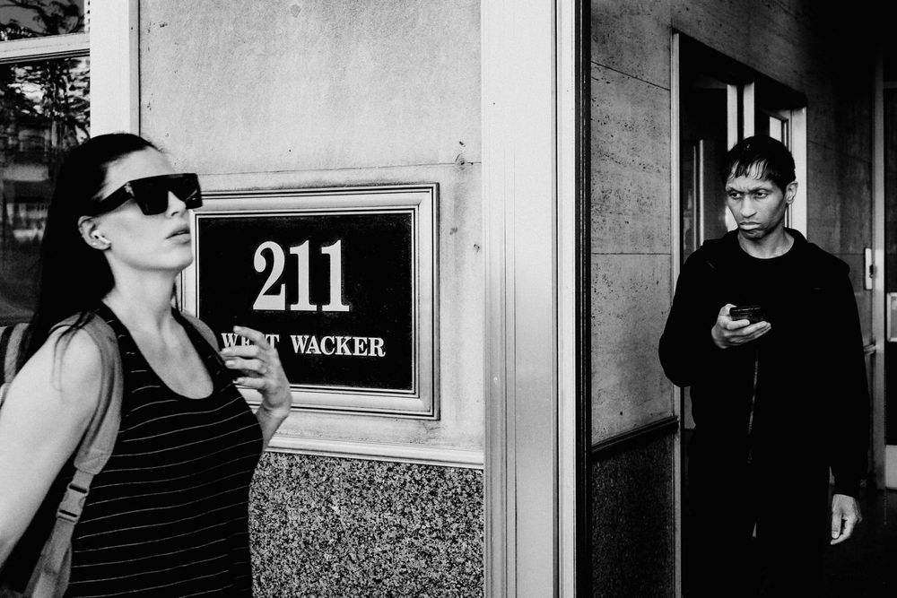 Woman walking by, man staring at her, stark hierarchical difference, downtown Chicago, black and white fine art photo.